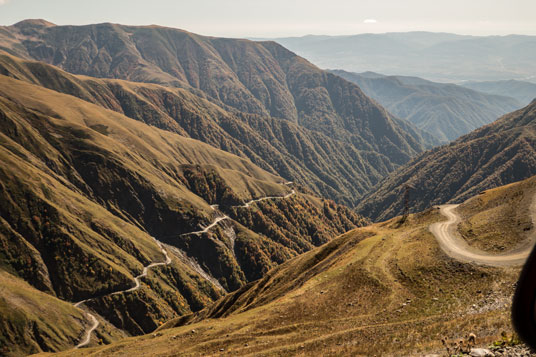 Blick von der Passhöhe auf die südliche Rampe der Piste, links der 2 Kilometer lange Abschnitt in 2200 Metern Höhe zwischen den beiden Abschnitten mit 7 und 5 Kehren, rechts die Piste oberhalb der 5 Kehren