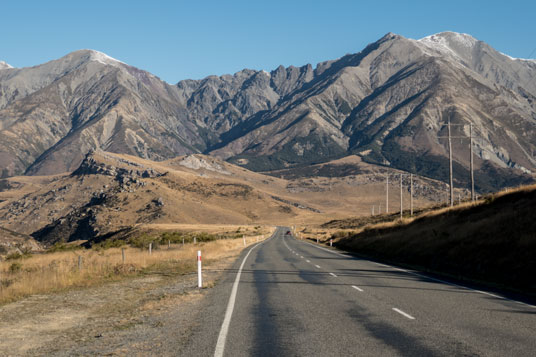 SH73 mit Castle Hill am linken Bildrand und Craigieburn Range im Hintergrund (ca. 2000 Meter)